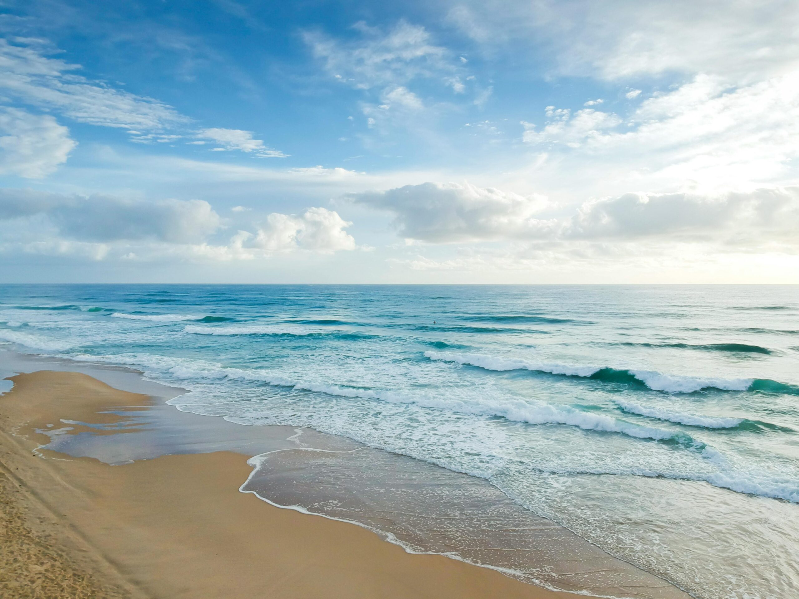 Sunset over a serene beach with gentle waves and soft sand, embodying beach bliss